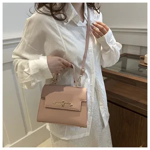 Détail du sac bandoulière rose avec texture litchi et fermoir doré rotatif élégant