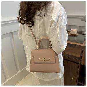 Photo lifestyle d'un sac à main rose clair en simili cuir avec fermoir doré sur chemise