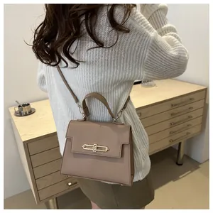 Détail du sac beige foncé motif litchi avec fermoir doré sur un meuble en bois