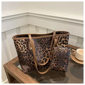Detail of leopard print tote bag set featuring matching coin purse and leather handles