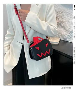 Detail view of pumpkin crossbody bag with red stitched eyes on model in white suit
