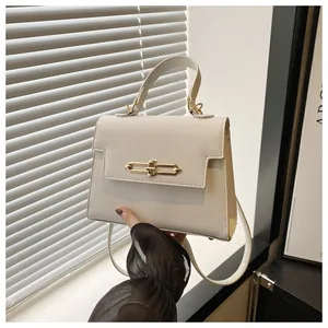 Détail du sac en cuir grainé blanc cassé avec boucle dorée sous une lumière douce