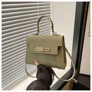 Détail d'un sac à main vert sauge en cuir grainé avec une boucle dorée à double anneau