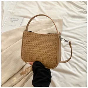 Détail montrant la texture tissée complexe et les ferrures argentées du sac beige