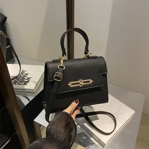 Sac à main élégant en cuir noir grainé avec fermoir doré et bandoulière réglable