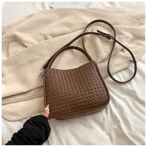 Détail de la texture tressée marron et de la bandoulière réglable du sac chic