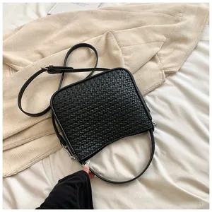 Détail d'un sac à main noir tressé avec ferrures argentées et bandoulière réglable sur tissu