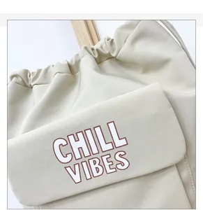 Detail van beige draagtas met Chill Vibes belettering en trekkoord canvas textuur