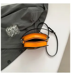 Top view of bright orange pumpkin crossbody bag with zipper and black strap details