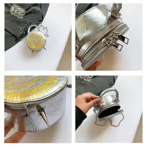 Détails du sac horloge argenté montrant la bandoulière chaîne, les pointes et le double zip