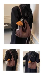 Détail du sac à bandoulière en daim givré marron foncé avec un joli pendentif en peluche