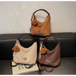 Vue détaillée de trois sacs hobo vintage en kaki, beige et marron sur un canapé en cuir
