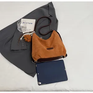 Gros plan sur le sac hobo en daim avec breloque ours sur un blazer gris chic