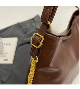 Detail of adjustable chain strap and leather texture on brown oversized tote bag