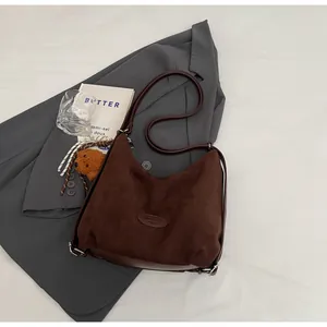 Détail du sac hobo en daim marron avec bandoulière réglable et breloque ours en peluche