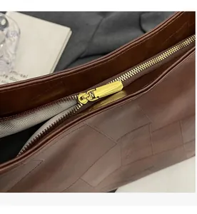 Detail of premium gold metal zipper and dark brown leather texture on a tote bag