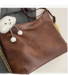Close-up of brown tote bag with quilted texture, chain strap, and cute cloud charm