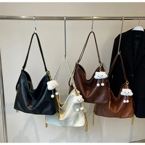 Detail of four large tote bags with gold chain tassels and cloud charms on a rack