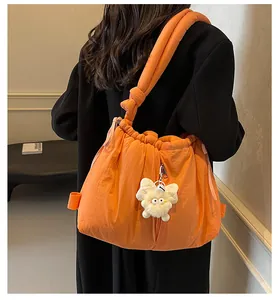 Detalle de bolso bandolera naranja acolchado con cordón y colgante de mariposa de felpa