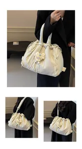 Detalle del bolso tote crema con cordón, peluche decorativo y textura de nailon