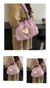 Detalle del bolso acolchado morado con correa de nudo y amuleto de monstruo de peluche