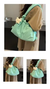 Detalle de bolso acolchado verde menta con cordón ajustable y colgante de gato suave