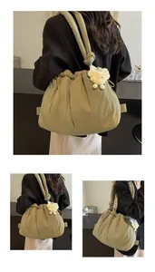 Detalle de bolso bandolera acolchado verde salvia con colgante de peluche y correa anudada