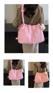 Detalle de bolso rosa claro con cordón y textura fruncida con un colgante de oveja