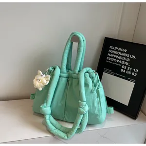 Detalle del bolso acolchado verde menta con asa de cuerda y colgante de peluche