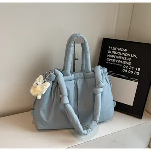 Primer plano de bolso acolchado azul claro con textura suave y accesorio de peluche