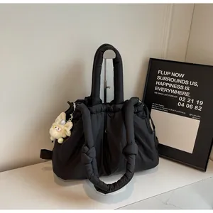 Detalle del bolso acolchado negro con cierre de cordón y colgante de peluche