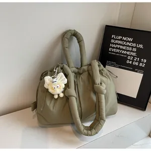 Detalle del bolso tote de nailon acolchado verde militar con cordón y peluche blanco