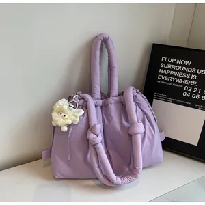 Detalle de bolso tote acolchado morado con asas de nudo acolchadas y colgante suave