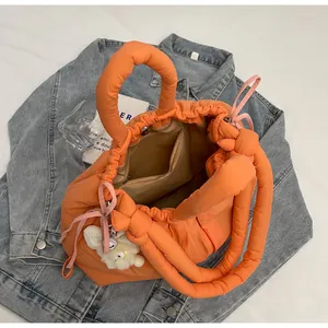 Detalle del interior del bolso acolchado naranja con cierre magnético y oso de peluche