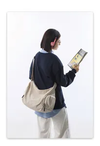 Détail de la bandoulière réglable et de la poche latérale sur un grand sac en nylon beige
