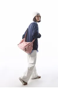 Détail d'un sac bandoulière en nylon rose avec sangle réglable porté par un mannequin