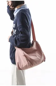 Vue latérale du grand sac hobo en nylon rose avec bandoulière réglable marron sur mannequin