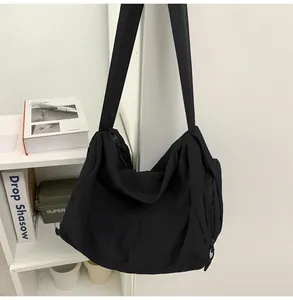 Détail du sac messager noir en nylon avec tissu imperméable et large bandoulière
