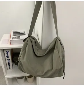 Détail du sac bandoulière en nylon vert olive montrant la texture et la double fermeture éclair