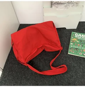 Gros plan du sac à bandoulière en nylon rouge imperméable avec sangle large et fermeture