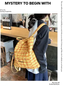 Dettaglio dello zaino a scacchi gialli con ricamo del logo Kazevo e chiusura a cordoncino