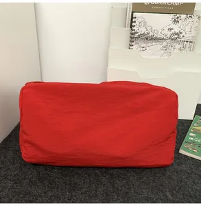 Détail d'un sac bandoulière en nylon rouge à texture froissée sur fond de feutre gris