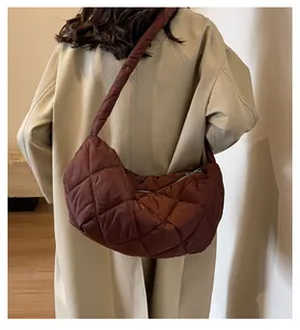 Detail of large brown quilted crossbody bag with soft padded texture and wide shoulder strap