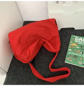 Gros plan du grand sac bandoulière en nylon rouge sur surface grise pour étudiants