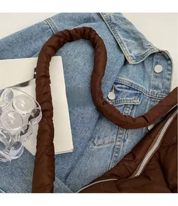 Detail of smooth shoulder strap and quilted texture on brown crossbody dumpling bag