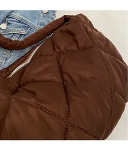 Close-up of brown quilted crossbody bag with silver zipper and puffy nylon texture