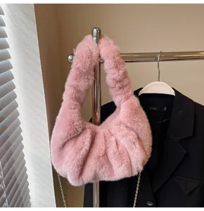 Détail du sac bandoulière en fausse fourrure rose avec design froncé et chaîne dorée