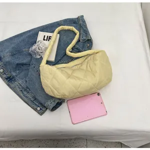 Detail of light yellow quilted puffy shoulder bag with diamond pattern and metal zipper