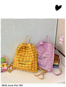 Dettaglio di zaini a scacchi con coulisse in giallo e rosa con tasche frontali zip