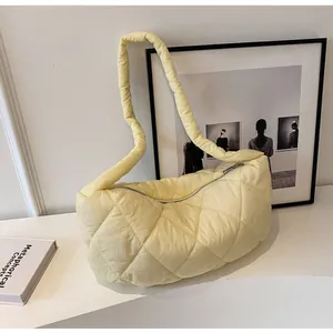 Close-up of a quilted light yellow shoulder bag with diamond stitching and top zipper
